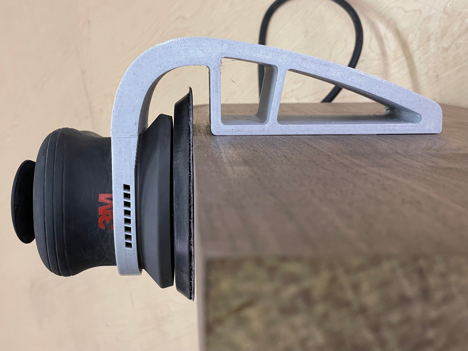 Xact90 guide mounted on an orbital sander against the edge of a wooden board